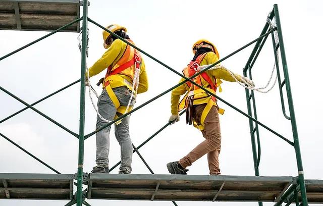 Two workers wearing harnesses and hard hats on scaffolding, as pictured in the course’s scaffolding safety lecture.